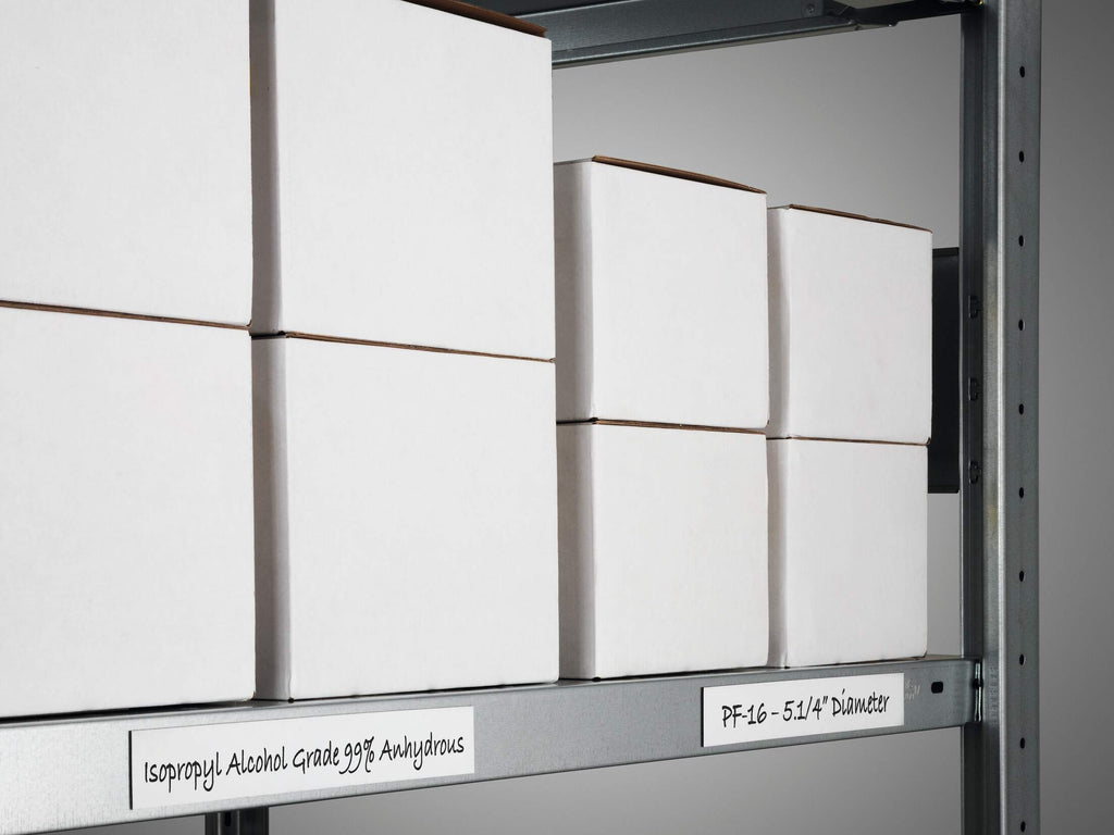 Handwritten white magnetic tape labels along a grey steel shelf with boxes