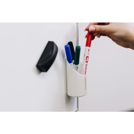 White Quartet accessory cup QTACCCUP on a whiteboard holding blue, black, green and red markers while a hand lifts the red one, black mini eraser beside the cup